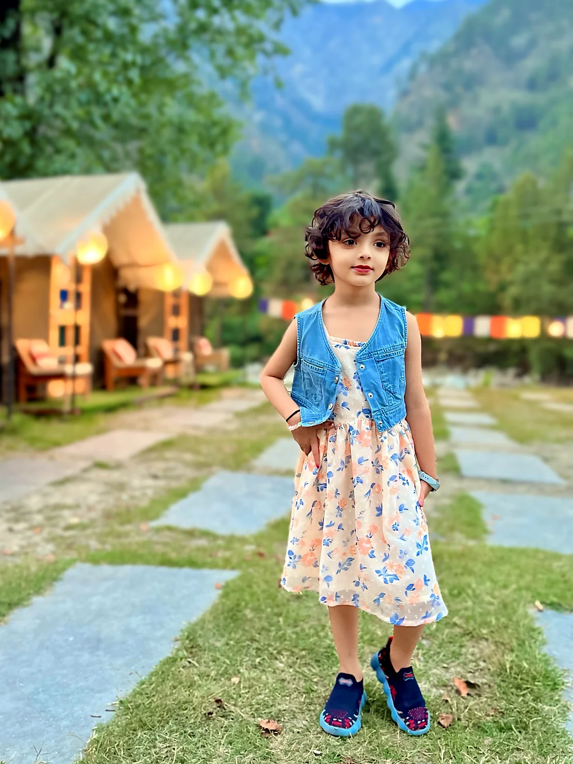 Nityaah in a floral dress and denim jacket in the mountains