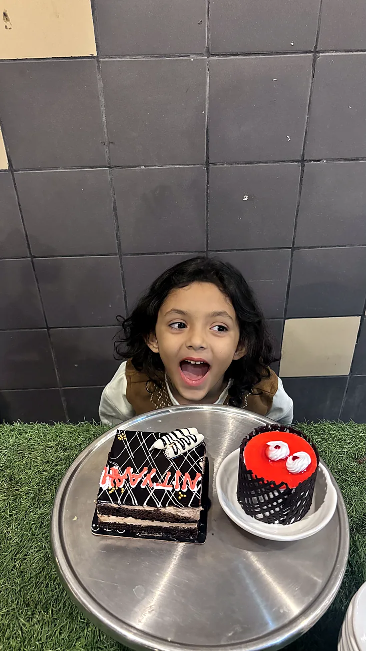 Nityaah pulling a face behind a birthday cake