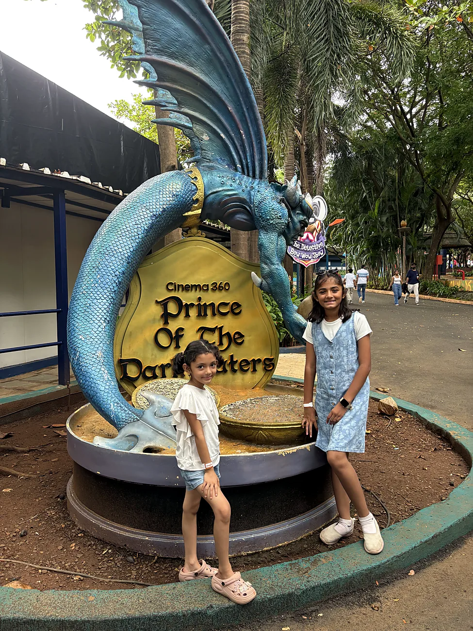 The sisters beside a dragon sculpture at a theme park