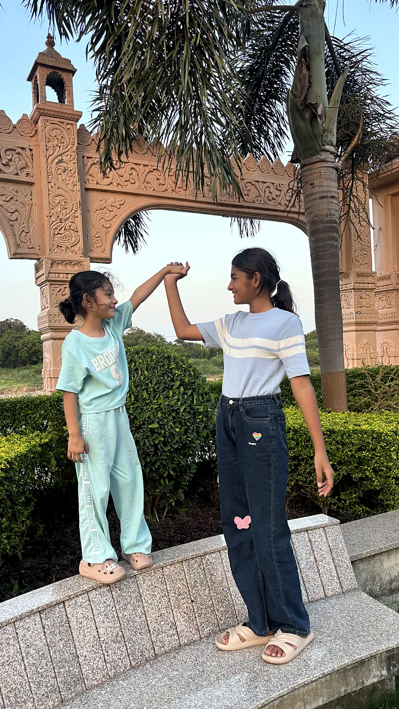 The sisters high-fiving under a carved archway