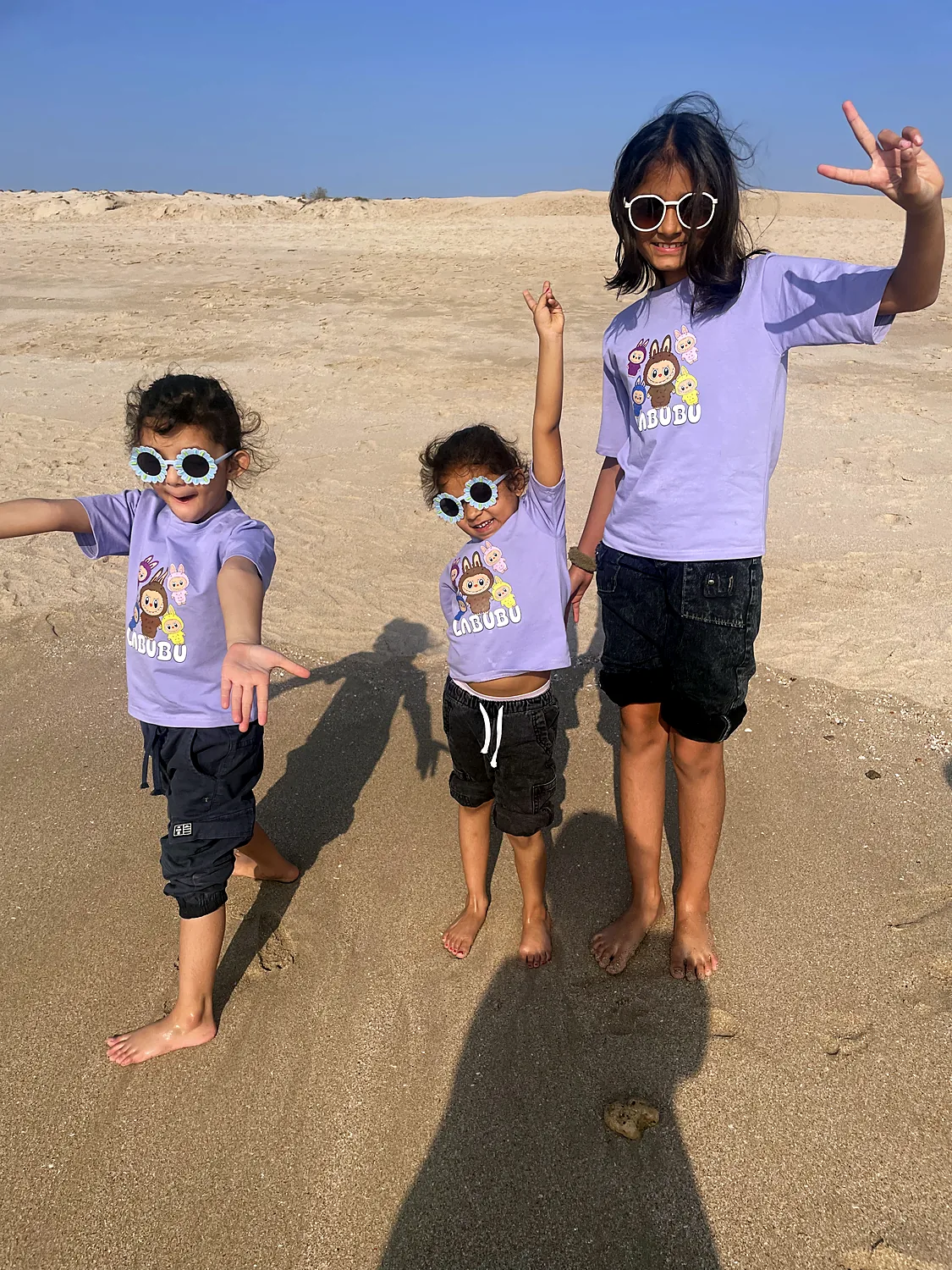 The sisters and a friend on the beach in matching t-shirts
