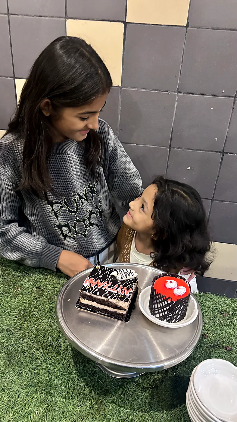 The sisters leaning in over a cake